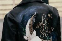 a black leather jacket painted for a celestial wedding, with blooms and a half moon is a gorgeous and romantic cover up idea