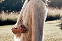 a blush fuzzy fur coat over a lace wedding dress to add a bit of edge to a romantic and glam bridal look