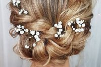 a braided low updo with a bump on top, some locks down and baby’s breath tucked in a cool idea for a boho bride