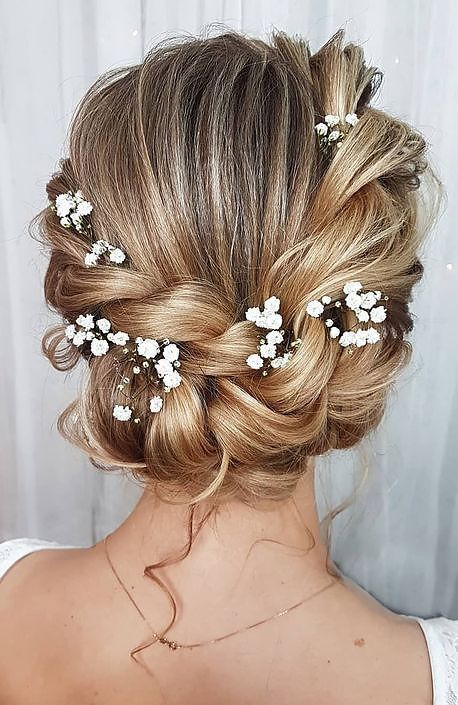 a braided low updo with a bump on top, some locks down and baby's breath tucked in a cool idea for a boho bride