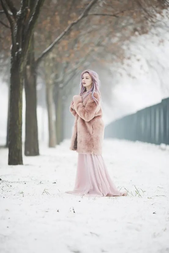 a bride with pastel hair rocking a pink A-line wedding dress with a tain and a pink faux fur coat for a dreamy and beautiful look