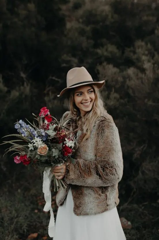 a brown faux fur bridal coat and a neutral hat are a nice idea for a fall or winter boho bride