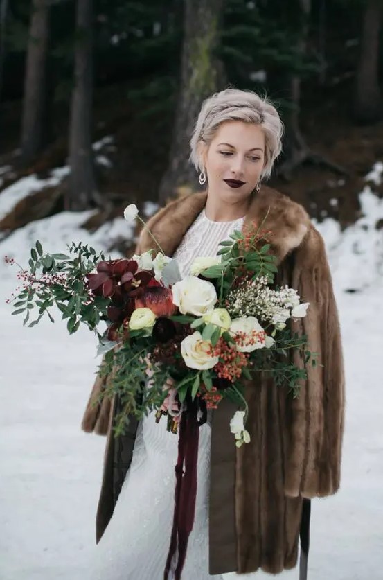 a brown fur coat, a dark lip and a moody wedding bouquet create a drama in this winter bridal look and add spice to it