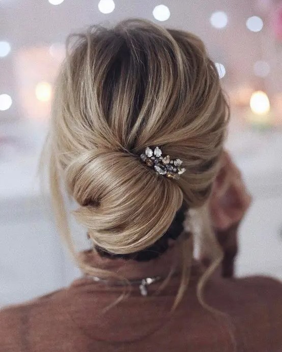 a casual messy updo with a twisted chignon and a rhinestone hairpiece to accentuate it