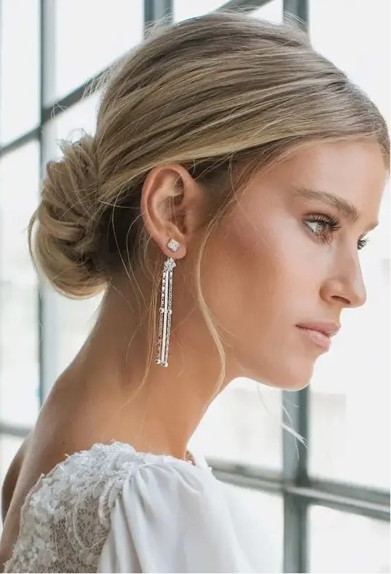 a classic low chignon with a volume on top and some locks down is a beautiful and cool hairstyle for a modern refined bride