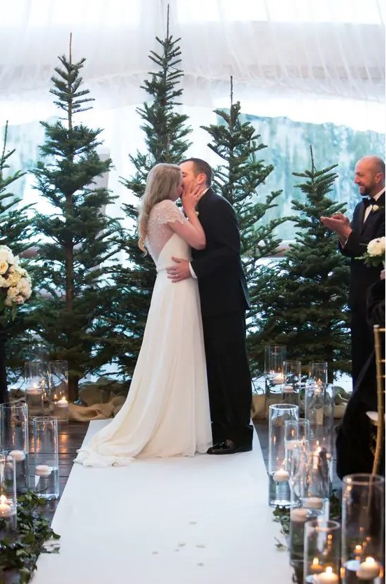 a classic winter wedding backdrop with evergreen trees, floating candles and greenery is a cool idea for a winter or Christmas wedding