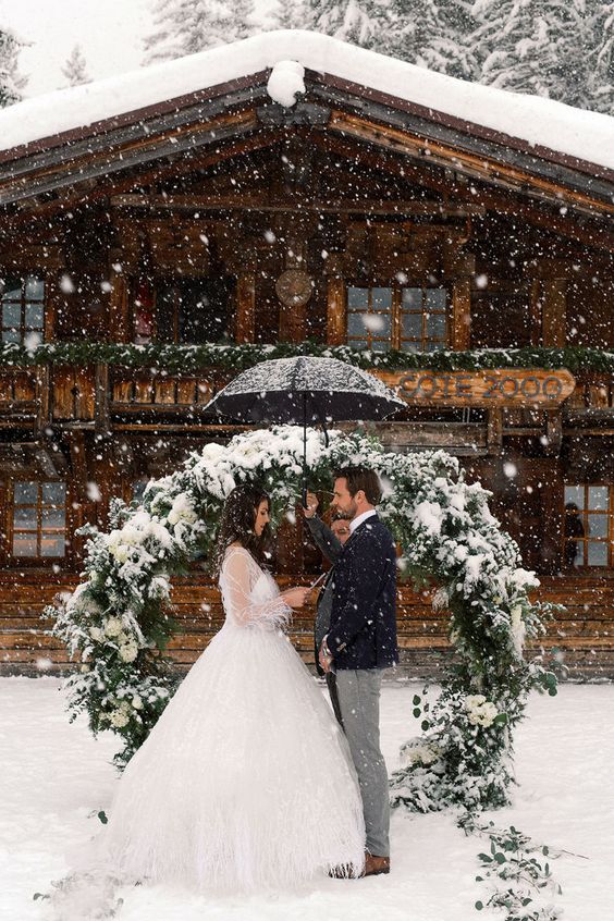 a classy round greenery wedding arch with white blooms and evergreens is a cool idea for a winter wedding