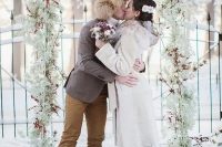 a frozen winter woodland wedding arch of baby’s breath, red berries and cotton is a lovely idea for a snowy wedding