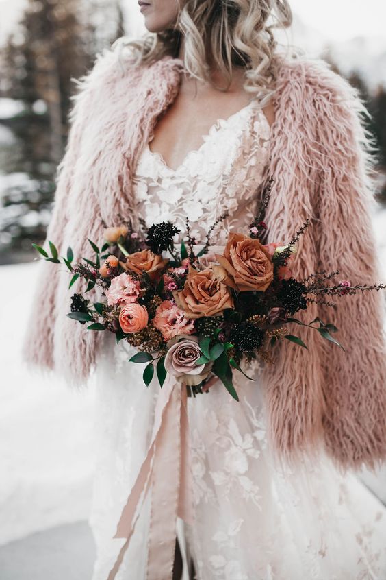 a fuzzy faux fur pink jacket paired with a floral applique wedding dress create a very delicate and soft bridal look