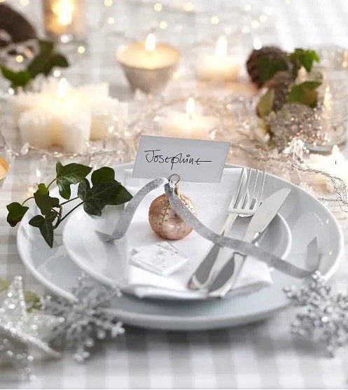 a glam Christmas tablescape with lights, star candles, glitter snowflakes, greenery and metallic ornaments