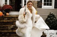 a glam bridal outfit with a strapless mermaid wedding dress, a white faux fur jacket and statement earrings for a winter celebration