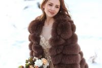 a glam gold embellished wedding dress paired with a brown faux fur jacket with short sleeves for a super glam winter bridal look