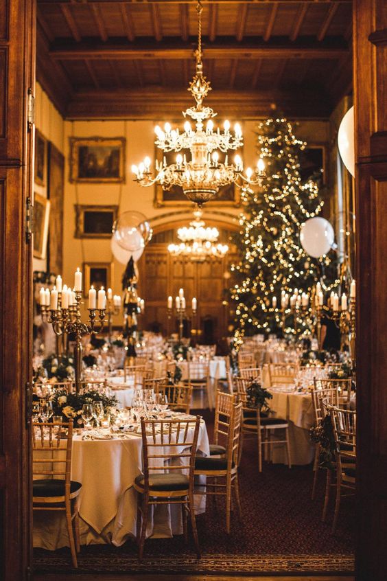 a gorgeous winter wonderland wedding reception space with lots of candles, a Christmas tree, evergreens and white blooms is wow
