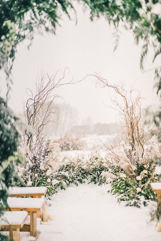 a green wedding altar on the ground plus a twig arch is a cool idea for an outdoor winter wedding with a rustic feel