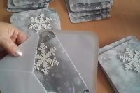 a grey wedding invitation suite with white 3D snowflakes and vellum jackets for them is a chic and lovely idea for a winter wedding
