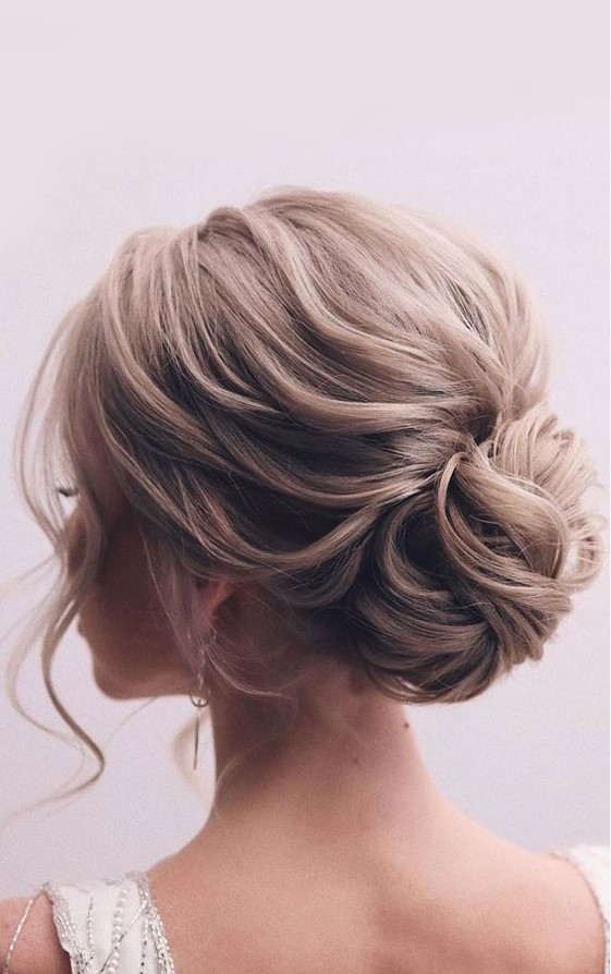 A loose low bun of wavy hair, wiht a wavy and voluminous top and face framing is a cool idea for an elegant bride
