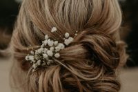 a loose messy low updo with a bump on top and some baby’s breath is a cool idea for a bride in any season
