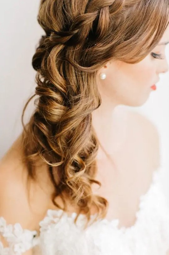 A lovely side swept half updo with a braided halo and waves down and face framing locks is adorable