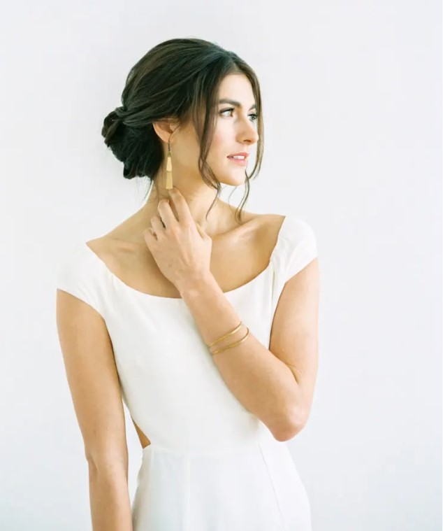 a low twisted bun hairstyle with a sleek top and some bangs is a chic and refined idea for a modern wedding
