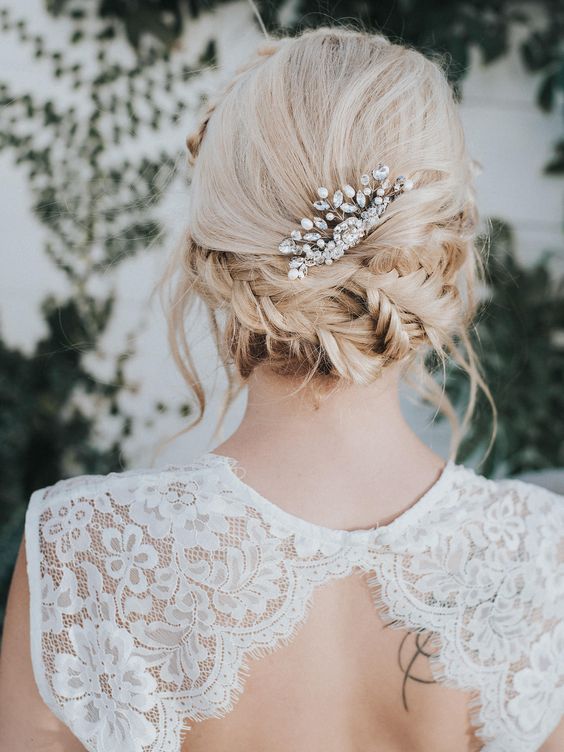 a messy braided low updo with a rhinestone hairpiece plus some locks down is a cool idea for any bride with medium length hair
