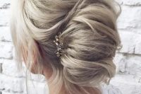 a messy casual chignon hairstyle with some waves down and a bump on top plus a rhinestone hairpiece