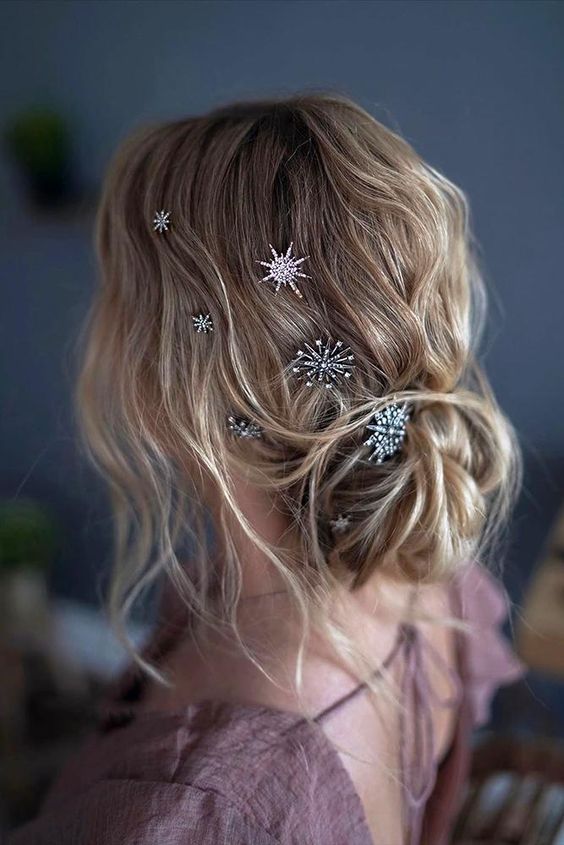 a messy loose low bun with a wavy top, some hair framing the face and a lot of shiny rhinestone hair pins is amazing