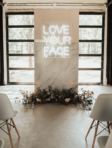 a minimalist wedding ceremony space done with a marble altar decorated with dried leaves, blooms and a neon sign