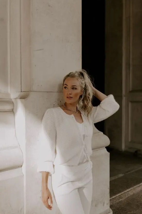 a modern and casual bride-to-be wearing white trousers and a top plus a light and semi-sheer cardigan on top