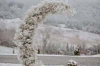 a moon-shaped white baby’s breath wedding altar is a creative idea for a winter wedding with a celestial feel