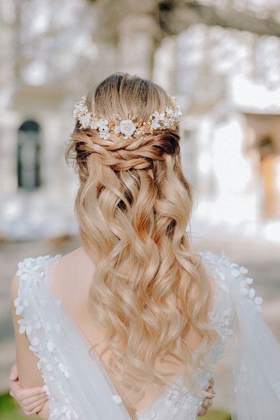 a pretty half updo with braids, waves down and a bump on top and a lovely floral headpiece is a stylish idea to rock