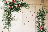 a red and green wedding arch with greenery, blooms and hanging agates for a trendy feel
