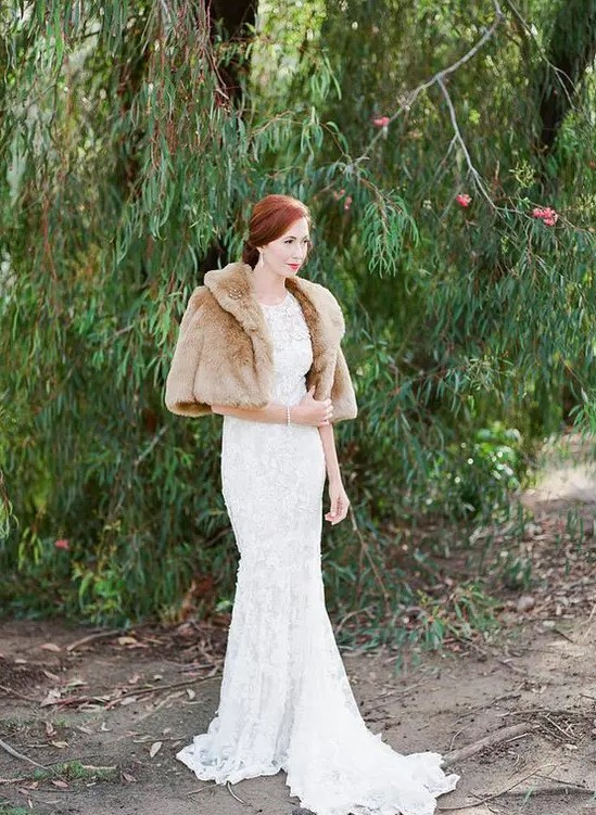 a refined and vintage-inspired winter bridal look with a lace mermaid wedding dress with a tail, a tan faux fur jacket with short sleeves