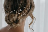 a romantic loose low ballerina bun with some pearl hair pins and flowers is a cool idea for a wedding, whatever the season is