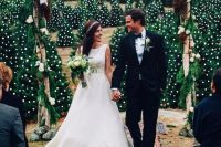a rustic winter wedding arch with evergreens, white blooms, leaves and oversized pinecones is a cool idea for a Christmas wedding