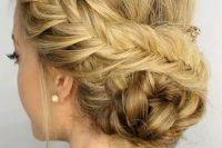a side fishtail braided updo with a bump on top and a braided low bun is a cool and stylish idea for a boho bridal look