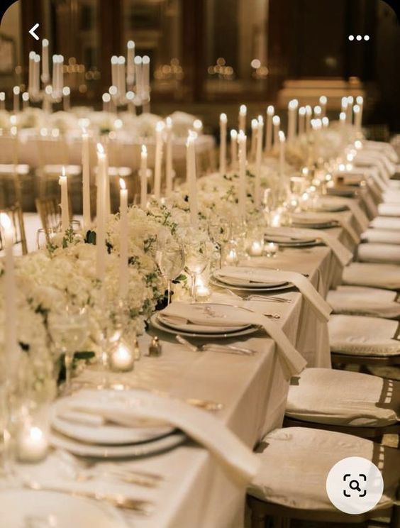 a sophisticated white winter wedding tablescape with lush wite florals and tall and thin candles is very chic and beautiful