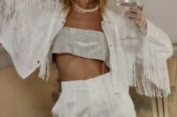 a sparkling white jacket with long fringe, a silver bandeau top and white high waisted pants for a party