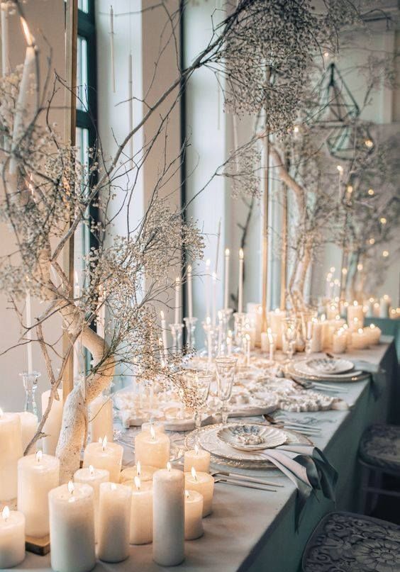 a unique winter wonderland wedding tablescape with pillar candles, frozen branches, neutral porcelain and linen