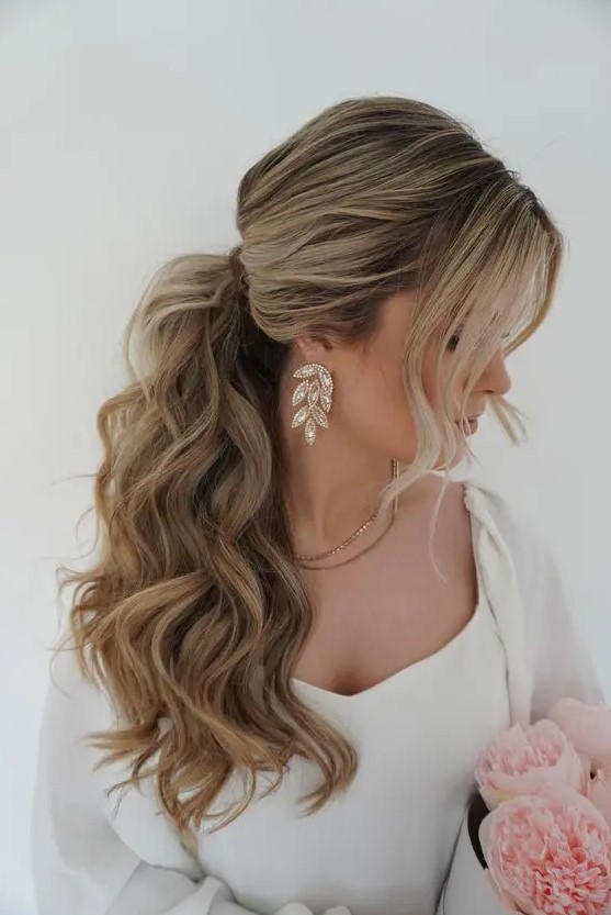 a voluminous wavy ponytail with a bump on top and face-framing hair is adorable for most bridal styles