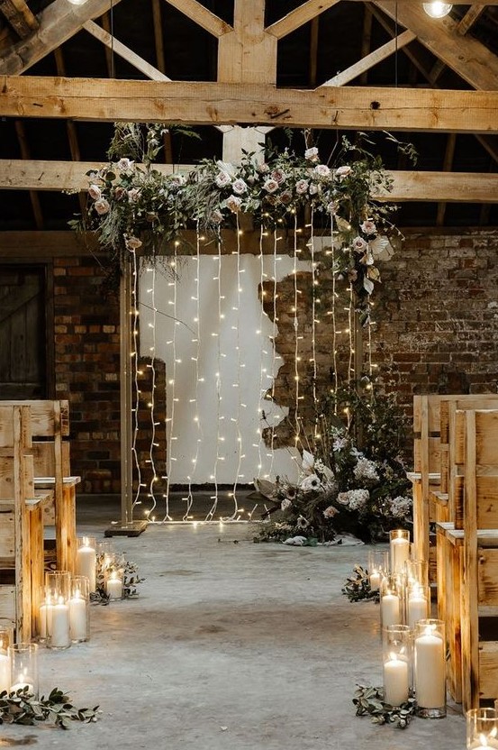 a wedding backdrop with lights and lush florals and greenery creates a romantic and welcoming ambience in the ceremony space