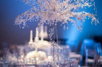 a white and silver winter wonderland wedding table with crystals and white blooms plus candles, silver chargers