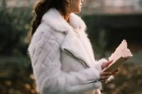 a white faux fur moto jacket is a unique outerwear option for a winter bride, it’s a fresh take on traditional fur coats