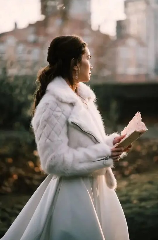 a white faux fur moto jacket is a unique outerwear option for a winter bride, it's a fresh take on traditional fur coats