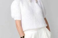 a white knit top with short sleeves, white high waisted wideleg trousers, statement silver earrings and a bracelet for a modern casual look