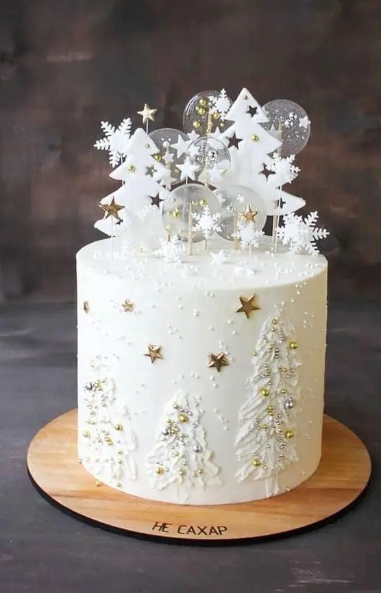a white winter wedding cake with frosting trees and edible beads as ornaments, sugar trees with stars and clear pops