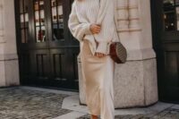 a winter outfit with an oversized sweater, a silk slip midi skirt, white booties and a brown crossbody bag