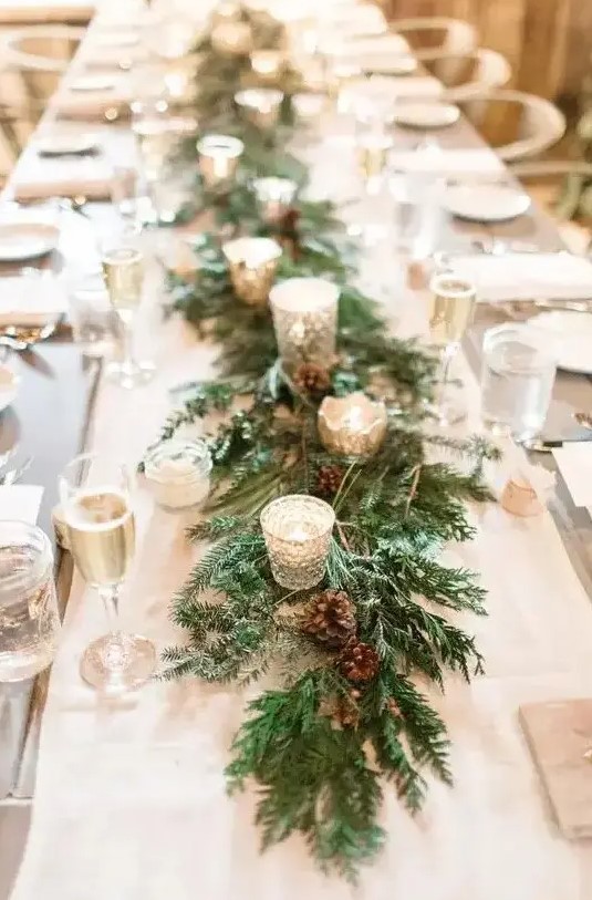 a winter wedding table runner of evergreens, pinecones and shiny candleholders with candles is a lovely idea for any type of winter wedding