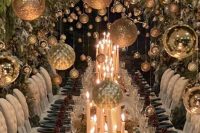 a winter wonderland wedding reception space with green plates, pinecones, silver ornaments, pillar candles and evergreens