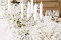 a winter wonderland wedding tablescape with candles, white blooms is a stylish idea if you want a fairy-tale