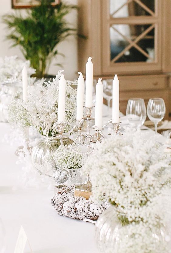 a winter wonderland wedding tablescape with candles, white blooms is a stylish idea if you want a fairy-tale